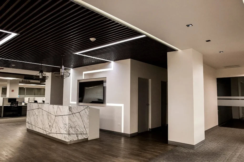 Interiorismo corporativo: Recepción moderna con diseño minimalista panel de mármol geométrico pantalla de televisión y luces led