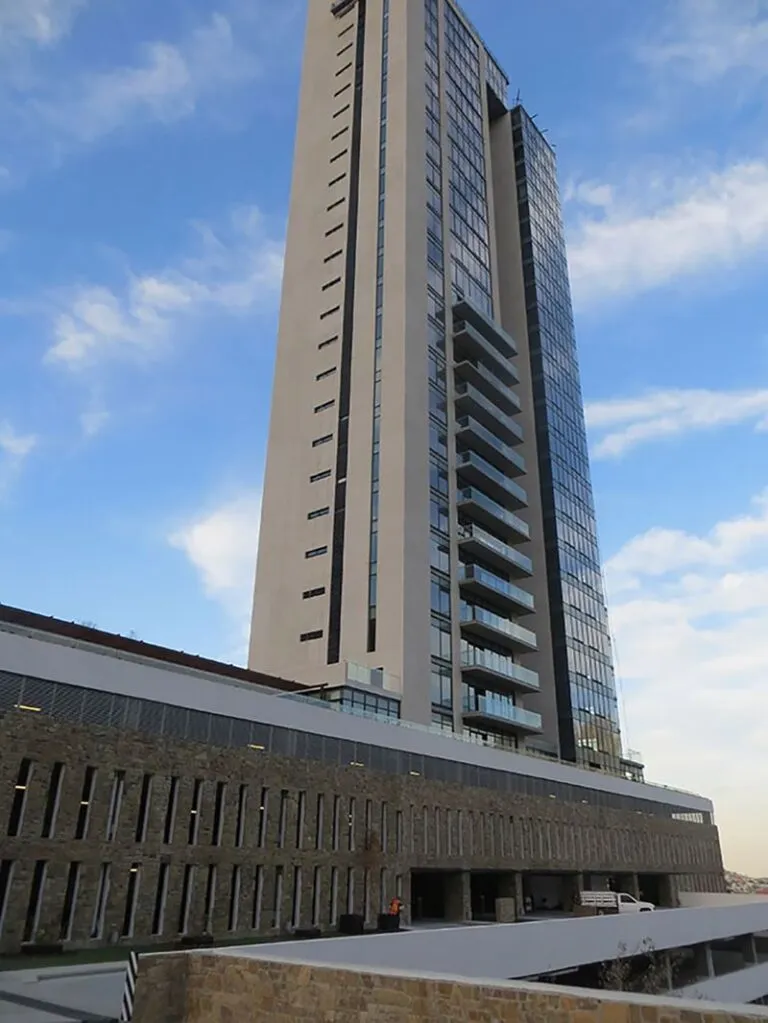 Vista en contrapicado de un edificio residencial de gran altura, mostrando su arquitectura y construcción con balcones escalonados.