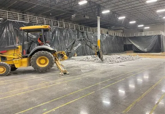 Operador de maquinaria pesada rompiendo losa de concreto reforzado para iniciar obras de construcción industrial