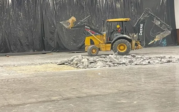 Maquinaria de carga frontal recolectando escombros tras la ruptura de firme en un sitio de construcción industrial