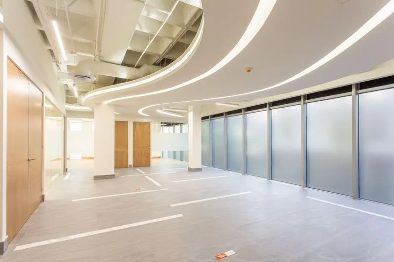 Diseño de arquitectura en Monterrey para espacios de trabajo con acabados en madera, pisos grises y ventanales amplios.