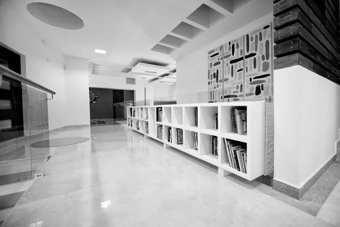 Pasillo minimalista con librero empotrado y detalles arquitectónicos en el techo para diseño y construcción de casas.