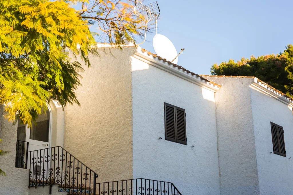 Una casa con arquitectura en Guadalajara que destaca por sus muros blancos texturizados y persianas oscuras