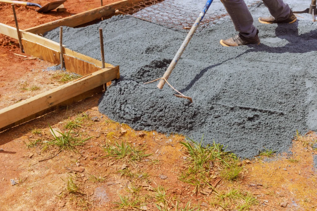 Trabajador utilizando herramientas manuales para extender material sobre los diversos tipos de suelo construcción hoy
