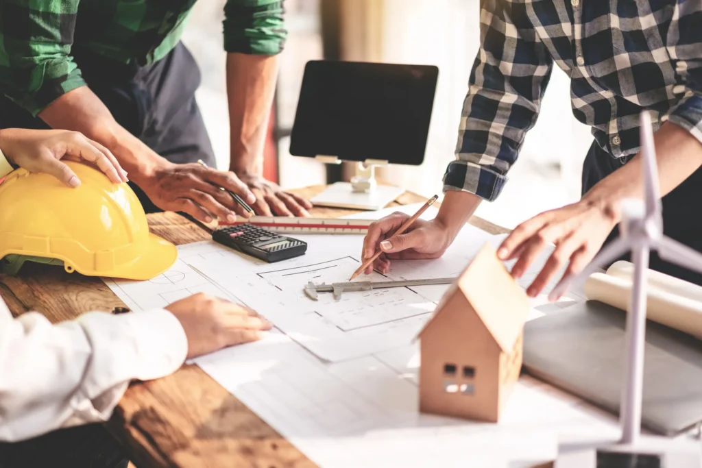 Arquitectos revisando planos para decidir si es mejor construir o comprar casa según el presupuesto de obra.