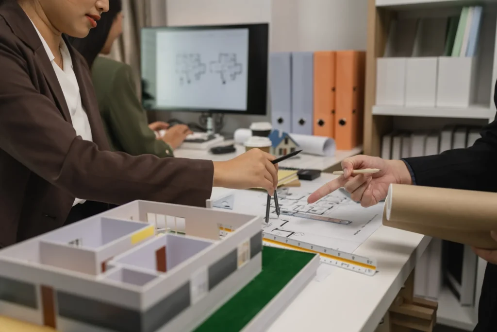 Arquitectos revisan planos con compás y regla en su estudio y dan seguimiento al desarrollo de una construcción.