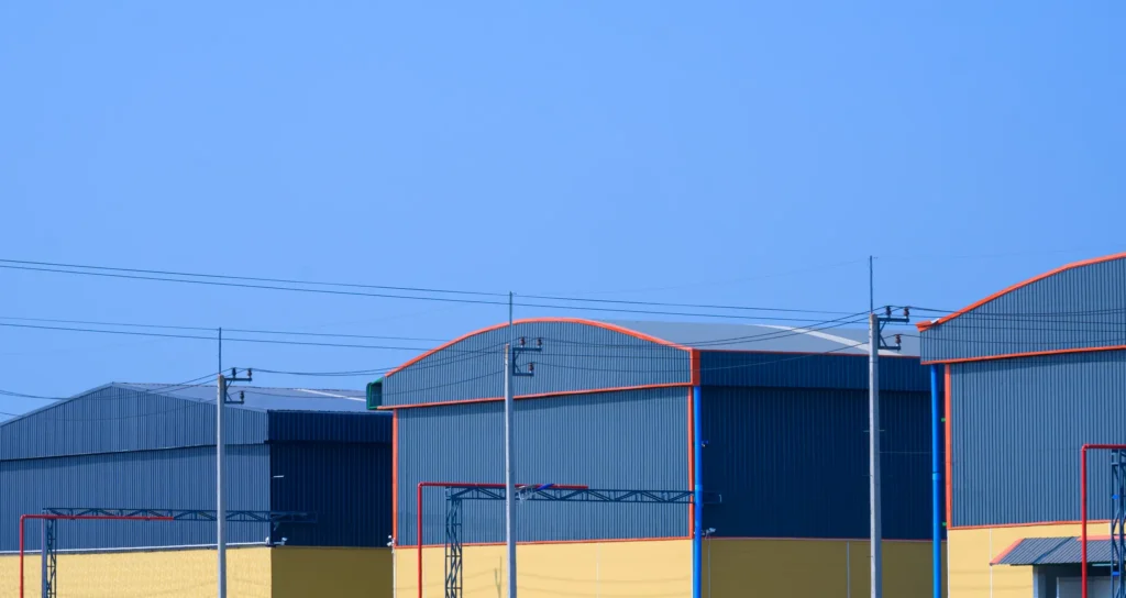 Exterior de varios tipos de naves industriales metálicas con fachadas azules y detalles amarillos bajo un cielo despejado.