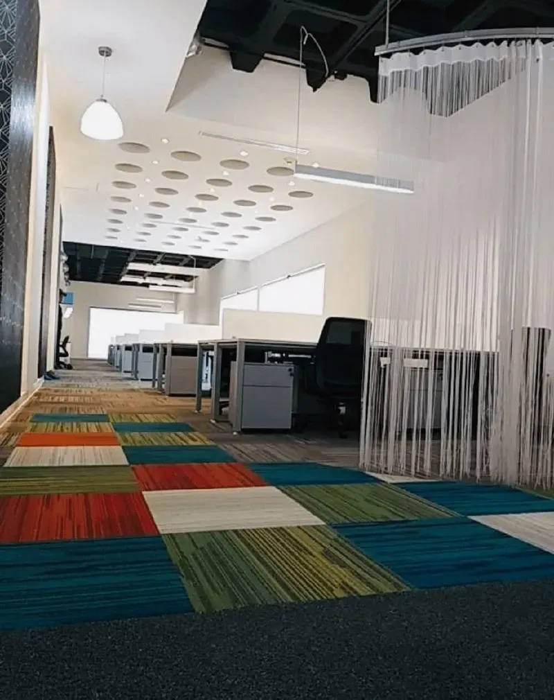 Oficina de planta abierta con alfombras de colores, construida por una constructora de oficinas.