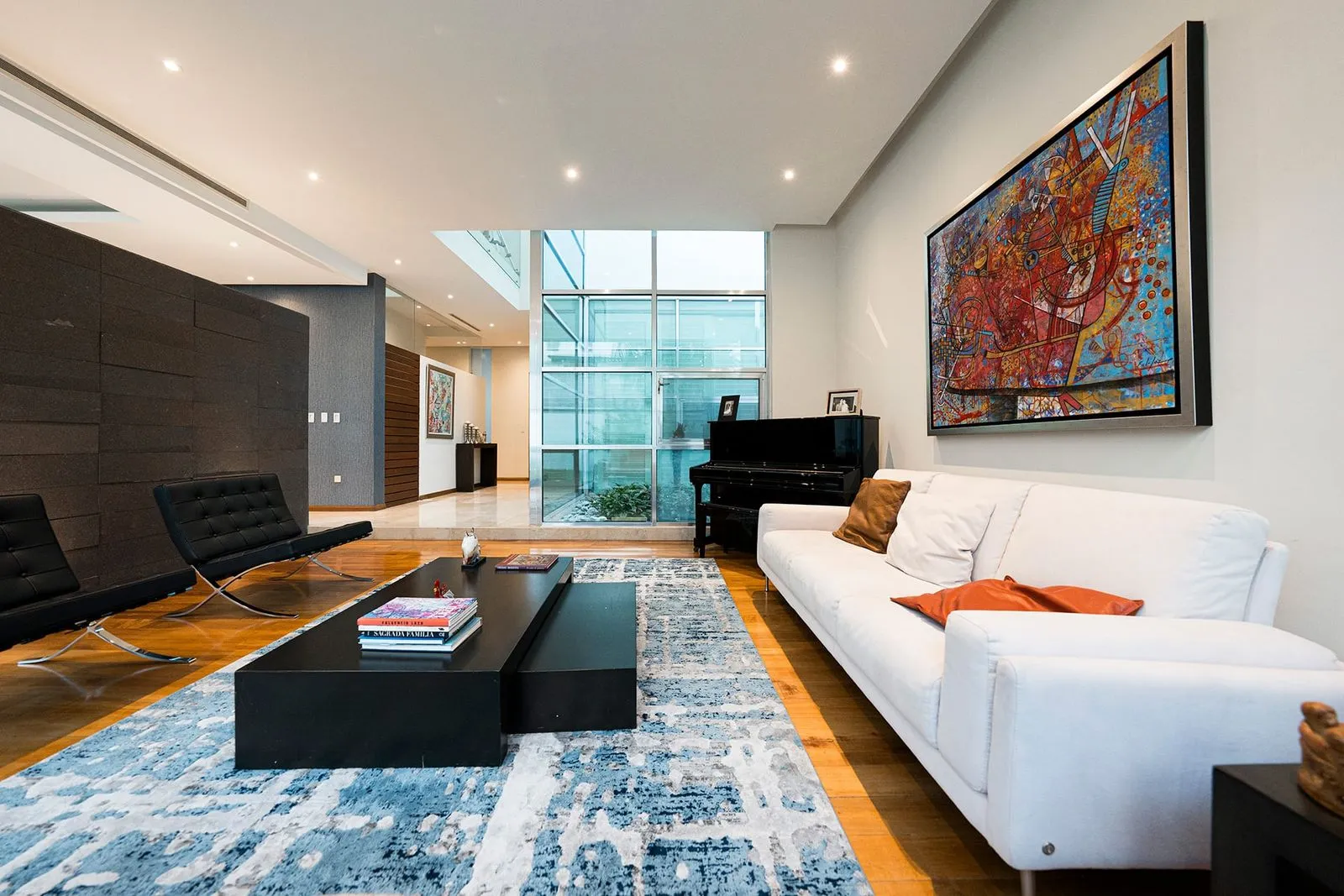 Espacio residencial de un despacho de arquitectos que muestra una elegante sala con piano de cola y acabados de lujo.