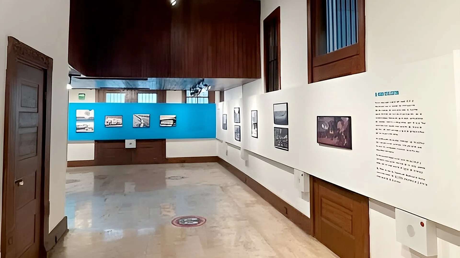 Galería de museo con arte y panel azul, diseñado por un despacho de arquitectos.
