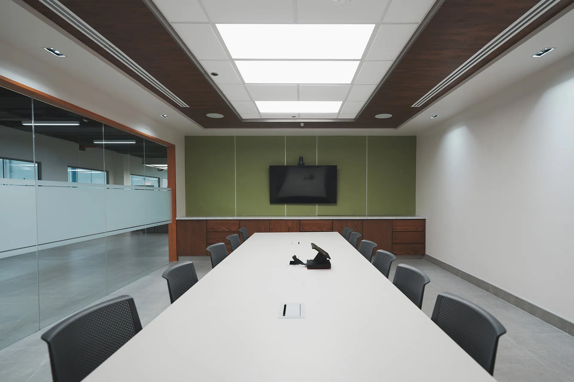 Moderno y minimalista diseño de sala de juntas para un despacho de arquitectos, con mesa blanca y mampara de vidrio.