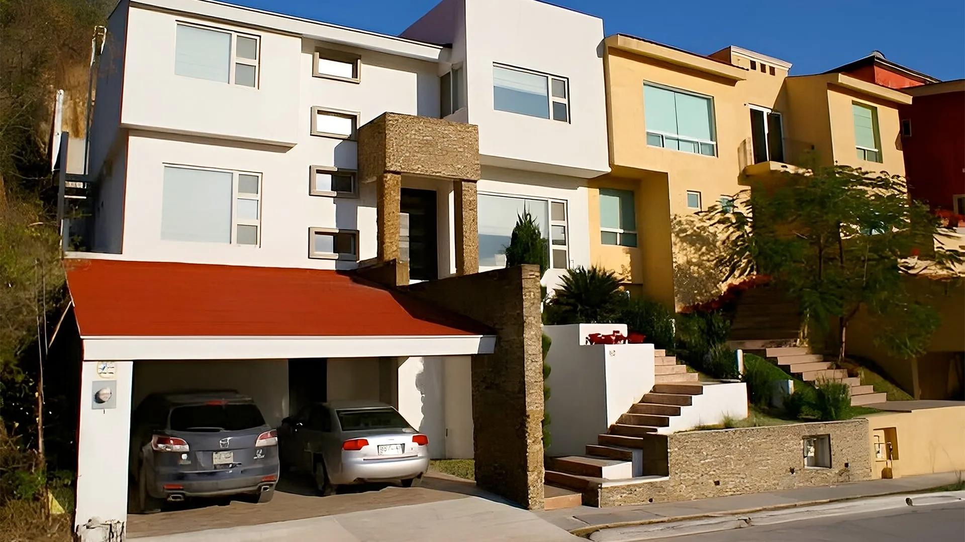 Fachada de casas residenciales en desnivel con cochera techada, un desarrollo de un despacho de arquitectos.