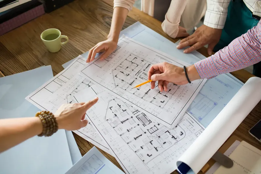 Profesionales de la construcción revisando planos y detalles constructivos sobre una mesa de madera.