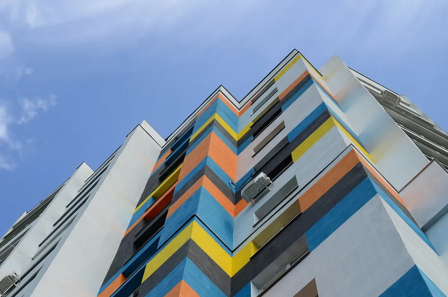 Colorida fachada arquitectónica de edificio moderno contra cielo azul.